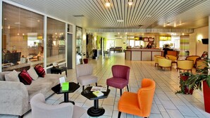 Un moderno vestíbulo de hotel con zona de estar, mostrador de recepción y bar.
