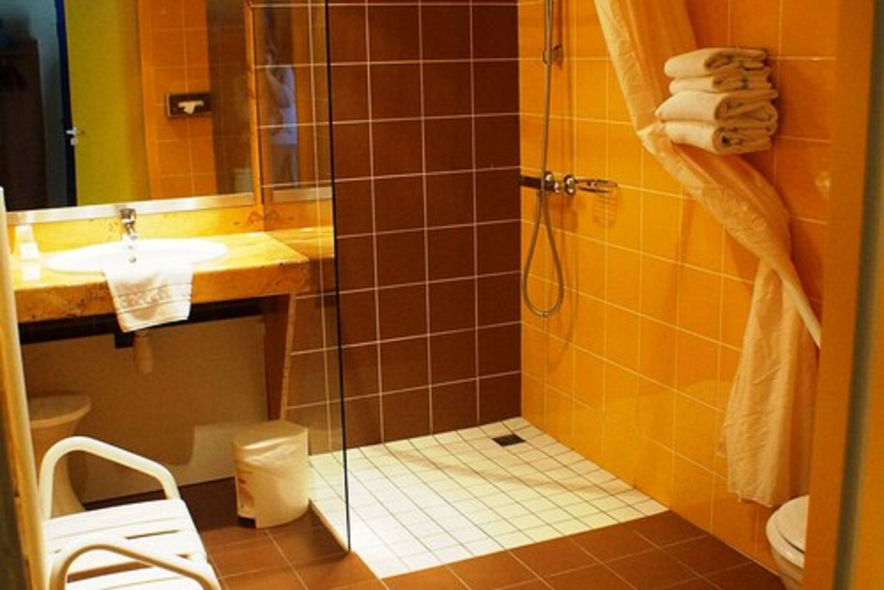 A bathroom with a glass shower enclosure, a sink with a towel, and a toilet.
