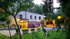 A building with a stone facade, outdoor seating area with chairs, and potted plants.