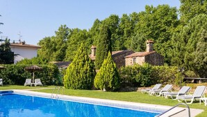 A swimming pool with lounge chairs and a stone building in the background.