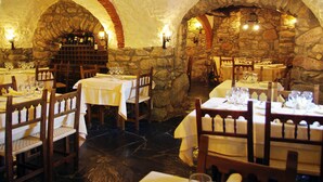 A restaurant with stone arches, wooden tables, and wine racks.