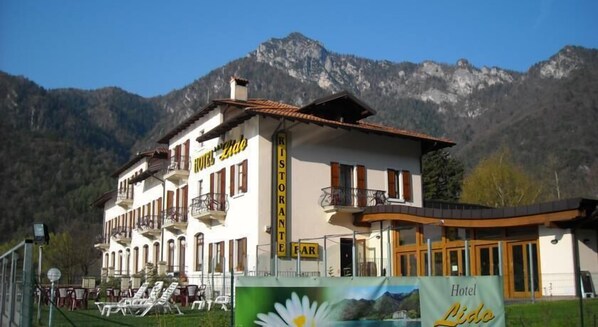 A hotel with a restaurant sign, balconies, and a mountain backdrop.