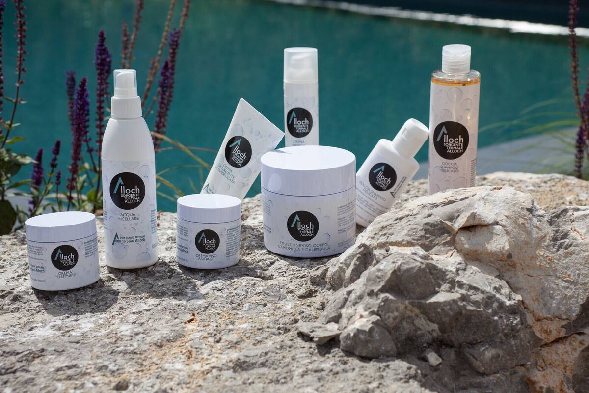 A collection of skincare products by Illoch on a rocky surface near a pool.