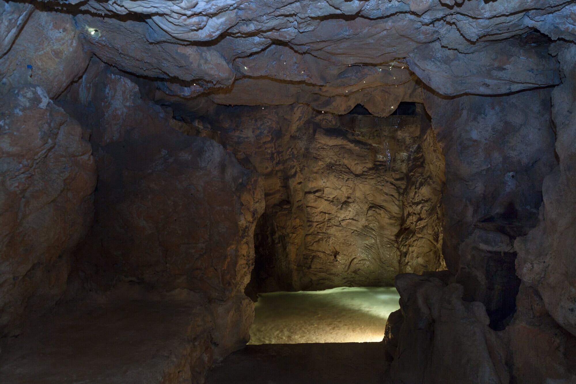 A cave interior with a central passageway and a small, illuminated chamber at the end.