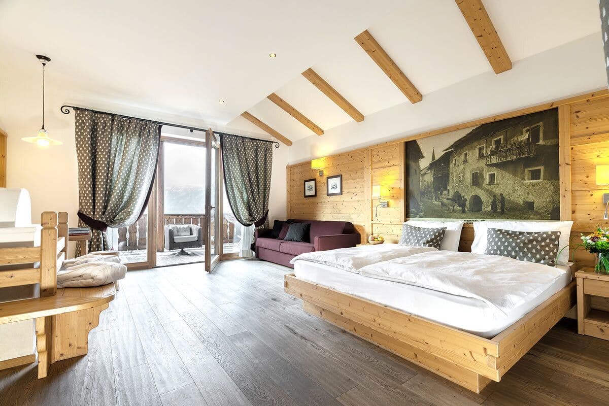 Une chambre à coucher avec un lit en bois, un canapé, une chaise et une grande fenêtre.