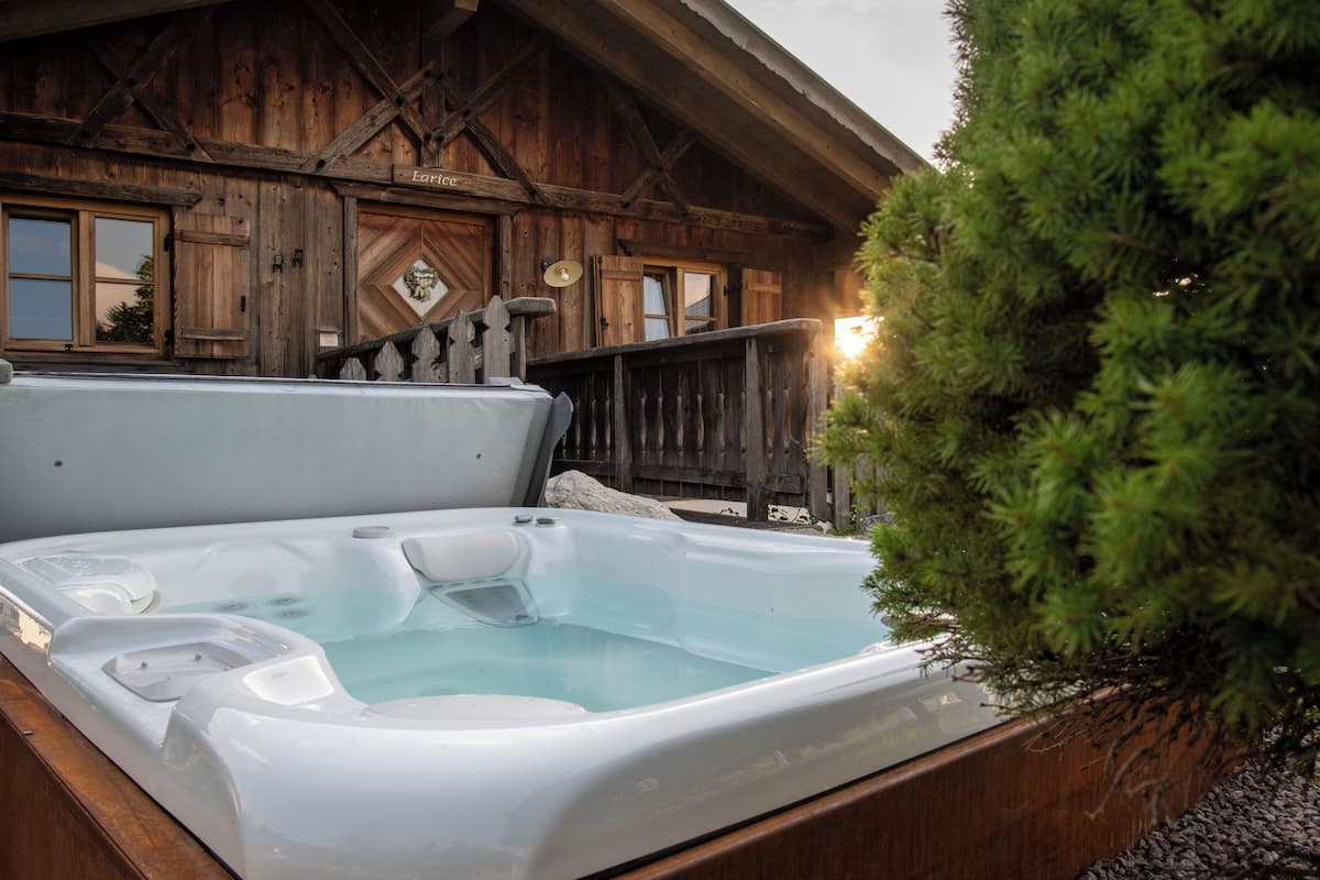 Une cabane en bois avec un jacuzzi et une terrasse en bois.