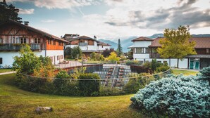 A traditional chalet-style building with a wooden facade, a stone staircase, and a view of mountains in the background. - Pineta Hotels Nature Wellness Resort (Predaia)