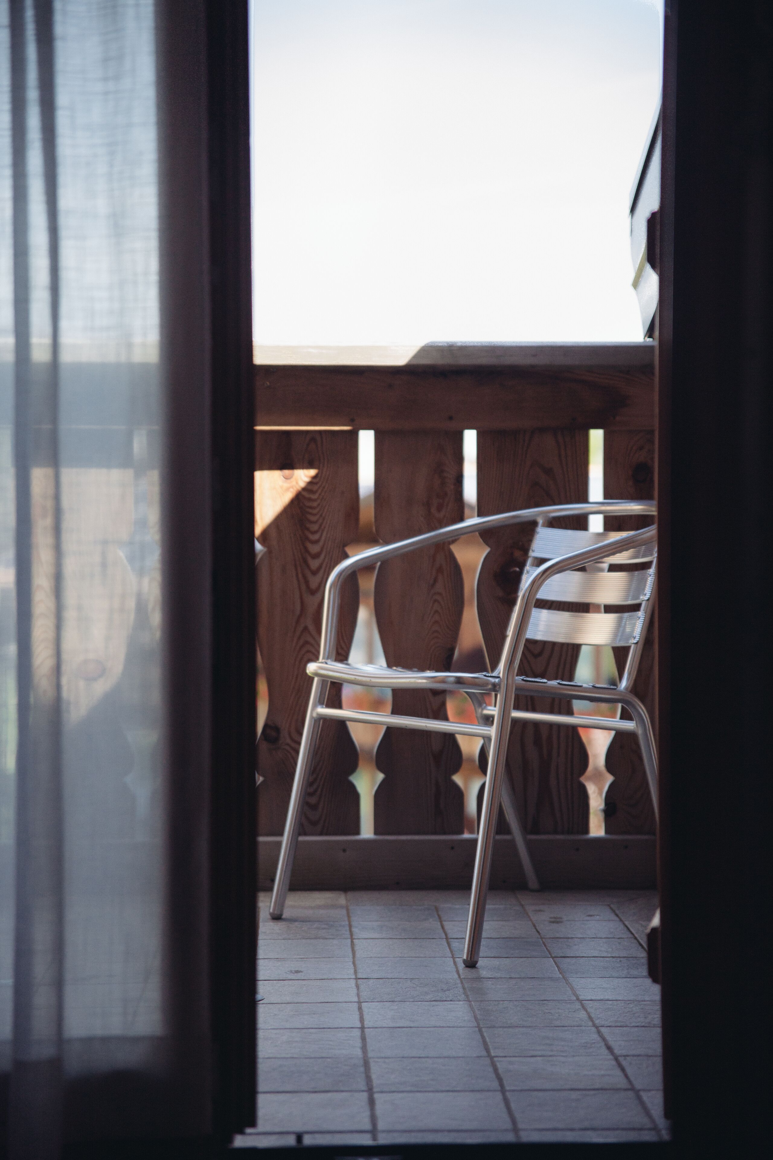 A balcony with a metal chair and a wooden fence.