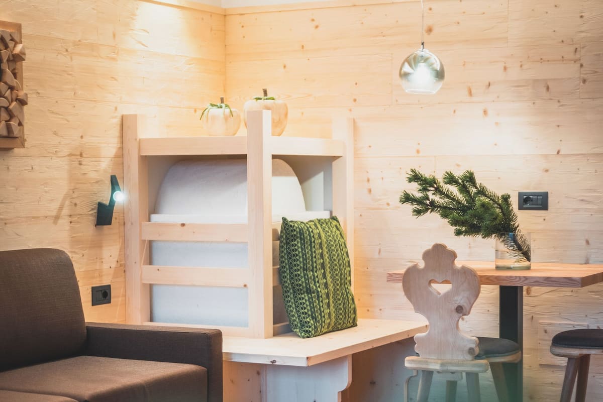 Une pièce chaleureuse et bien éclairée, avec des murs et un plancher en bois, un canapé, une table avec un livre et un luminaire suspendu.