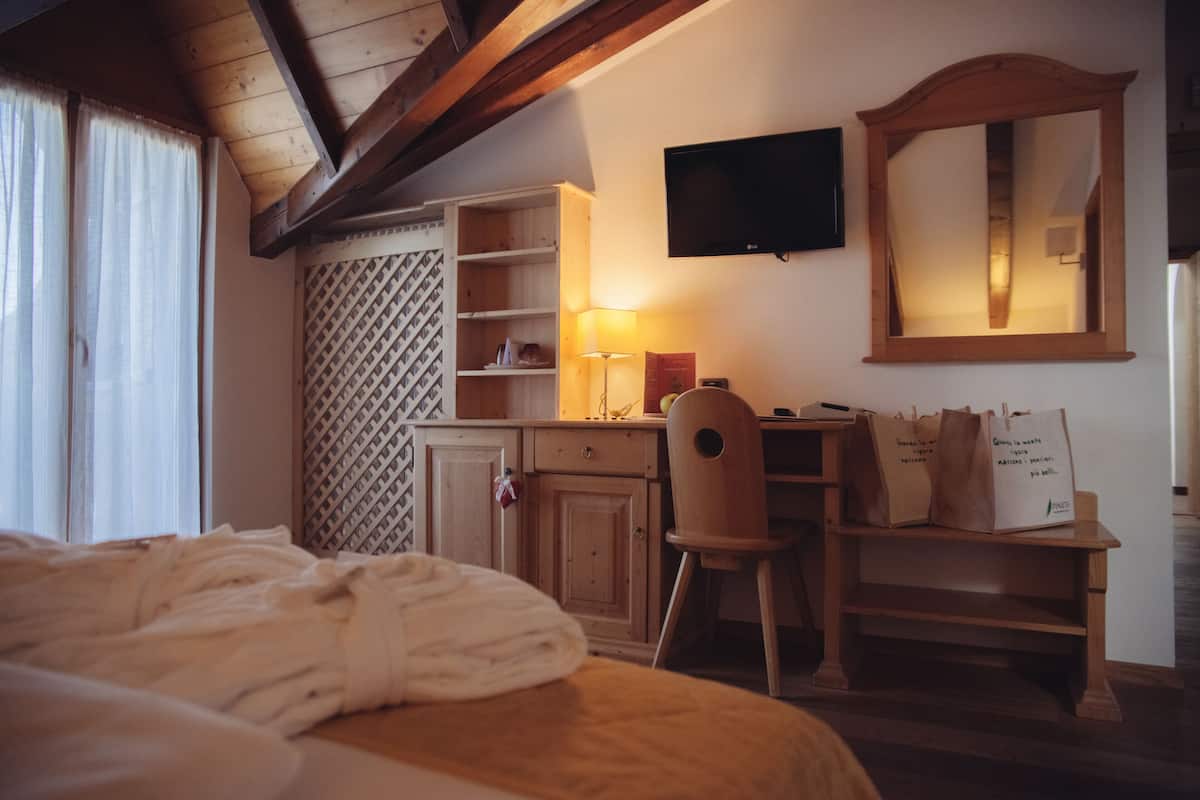 Une chambre à coucher comprenant un lit, un bureau en bois, une chaise et un téléviseur fixé au mur.