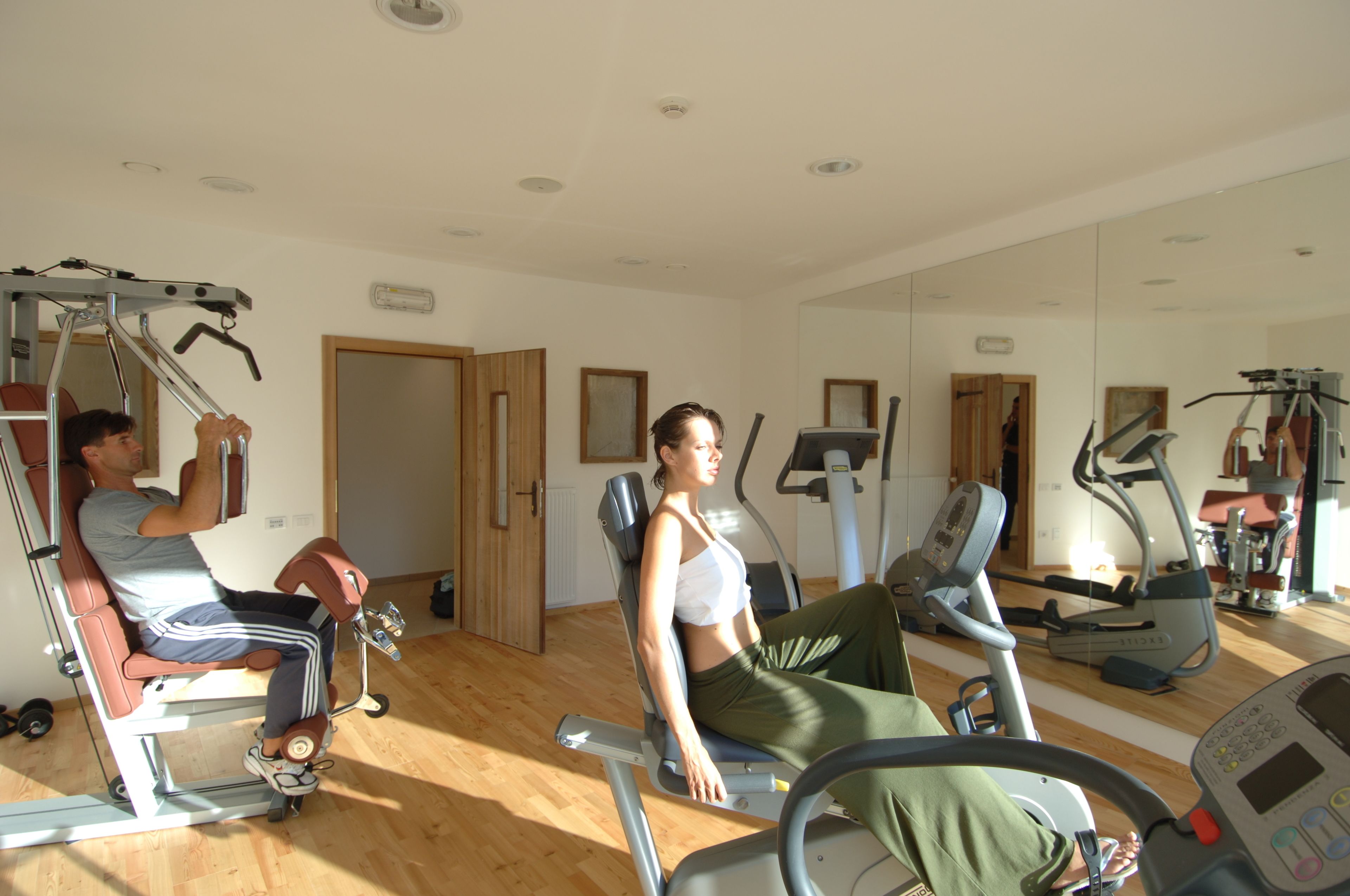 Una palestra con attrezzature per esercizi, pavimento in legno e un grande specchio.