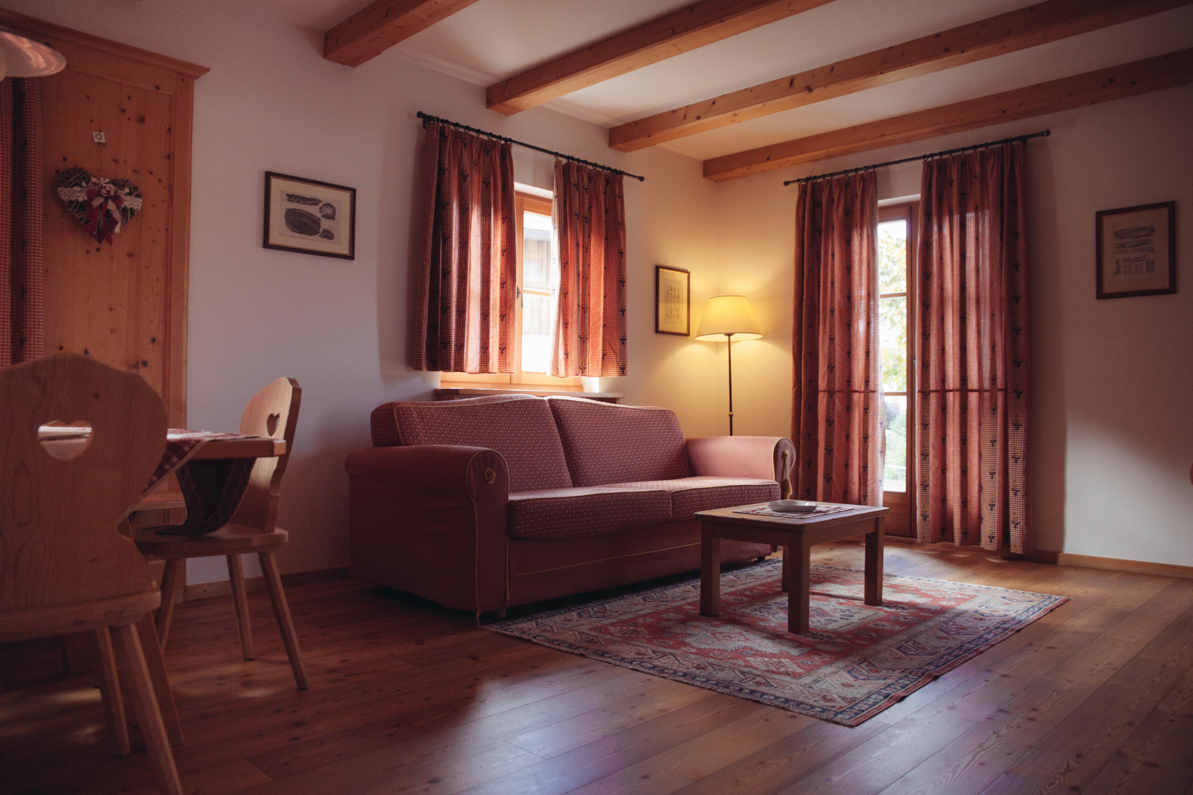 Un salon chaleureux avec un plancher en bois, un canapé, une table basse et une lampe.