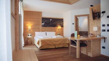 Una habitación con paneles de madera, una cama, un escritorio y un televisor montado en la pared.
