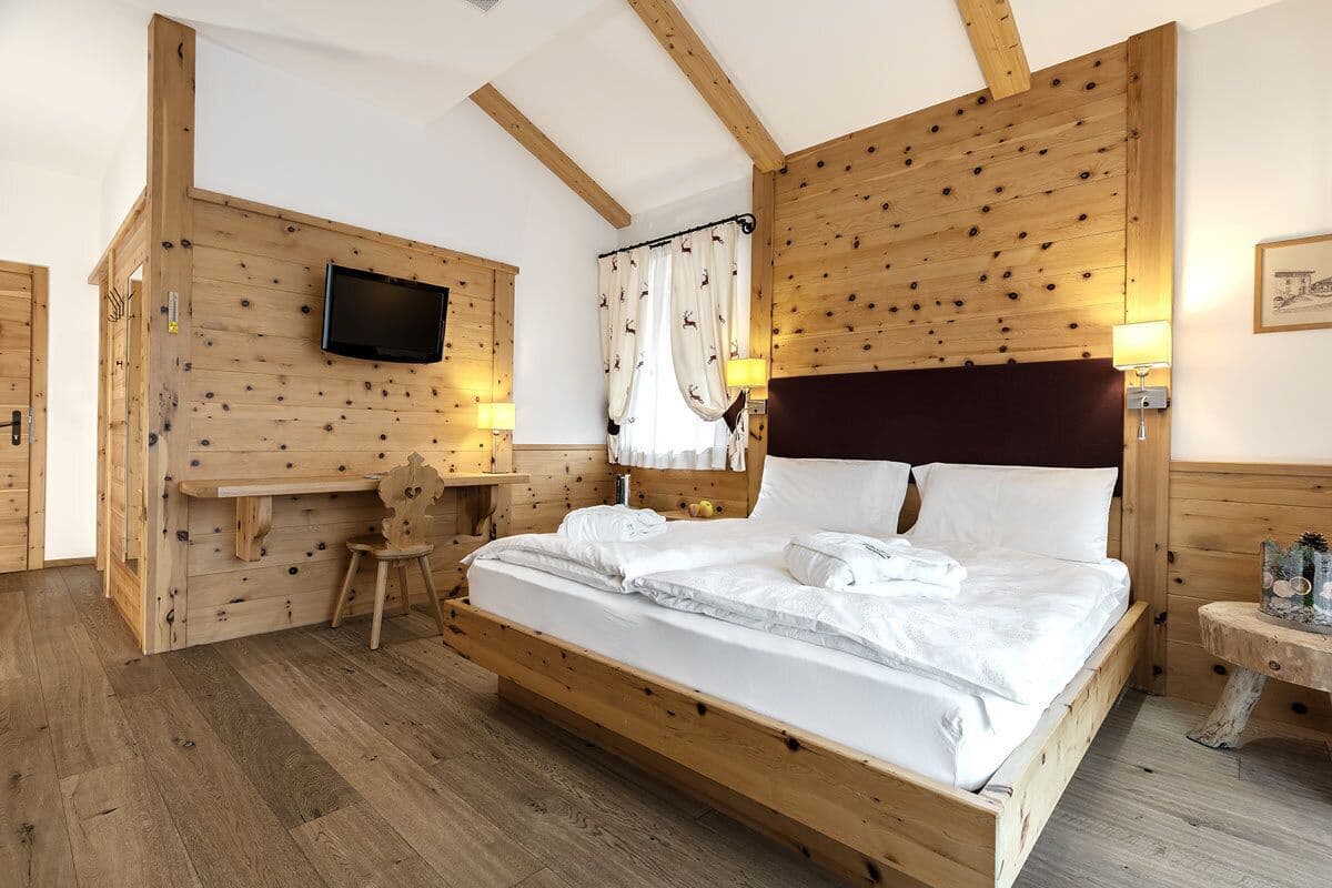 Une chambre à coucher en bois, avec un lit, un bureau et un téléviseur fixé au mur.