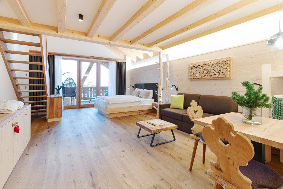 Une pièce spacieuse avec un lit en mezzanine, une table à manger en bois, un canapé et un escalier.
