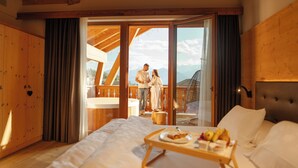 A bedroom with a large bed, a wooden headboard, and a breakfast tray on the bedside table. - Pineta Hotels Nature Wellness Resort (Predaia)