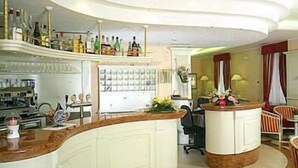 Zona de bar moderna con una barra curva, un área de estar con sillas a rayas y una estantería para vinos a la vista.