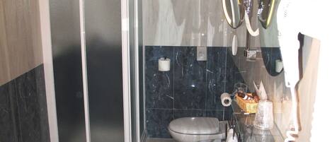 Uma casa de banho moderna com chuveiro em cabine de vidro, lavatório e sanita.