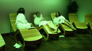 Three people relaxing in wooden lounge chairs in a room with a tiled floor. - Olisamir (Cavedago)