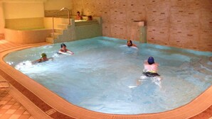 An indoor swimming pool with a tiled floor and a stone wall. - Olisamir (Cavedago)