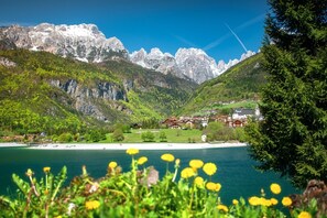 A mountainous landscape with a lake, a village, and a church. - Olisamir (Cavedago)