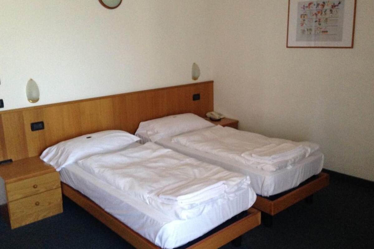 A double bed with two nightstands, a wall-mounted light, and a framed picture on the wall.
