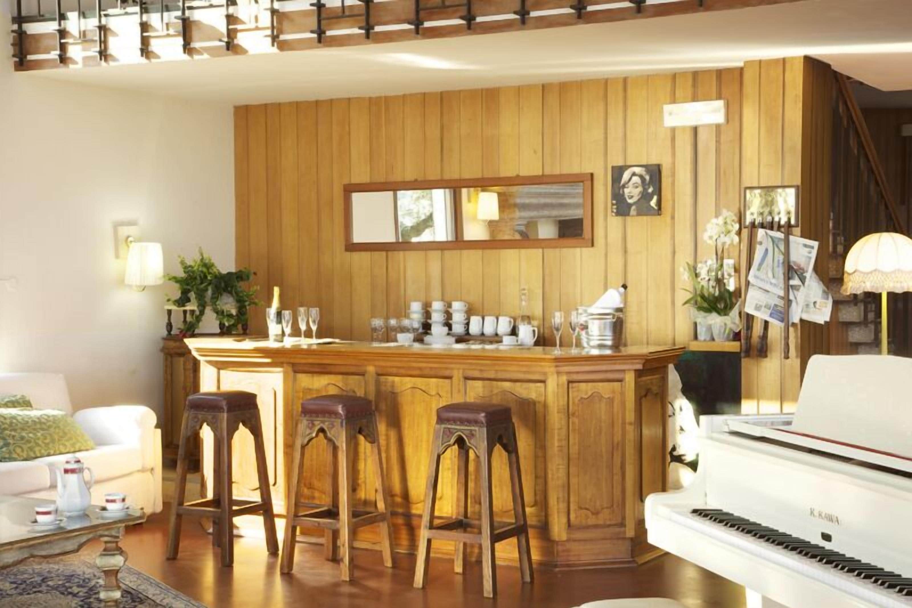 Un salon chaleureux avec un piano, un comptoir de bar en bois et un grand miroir.