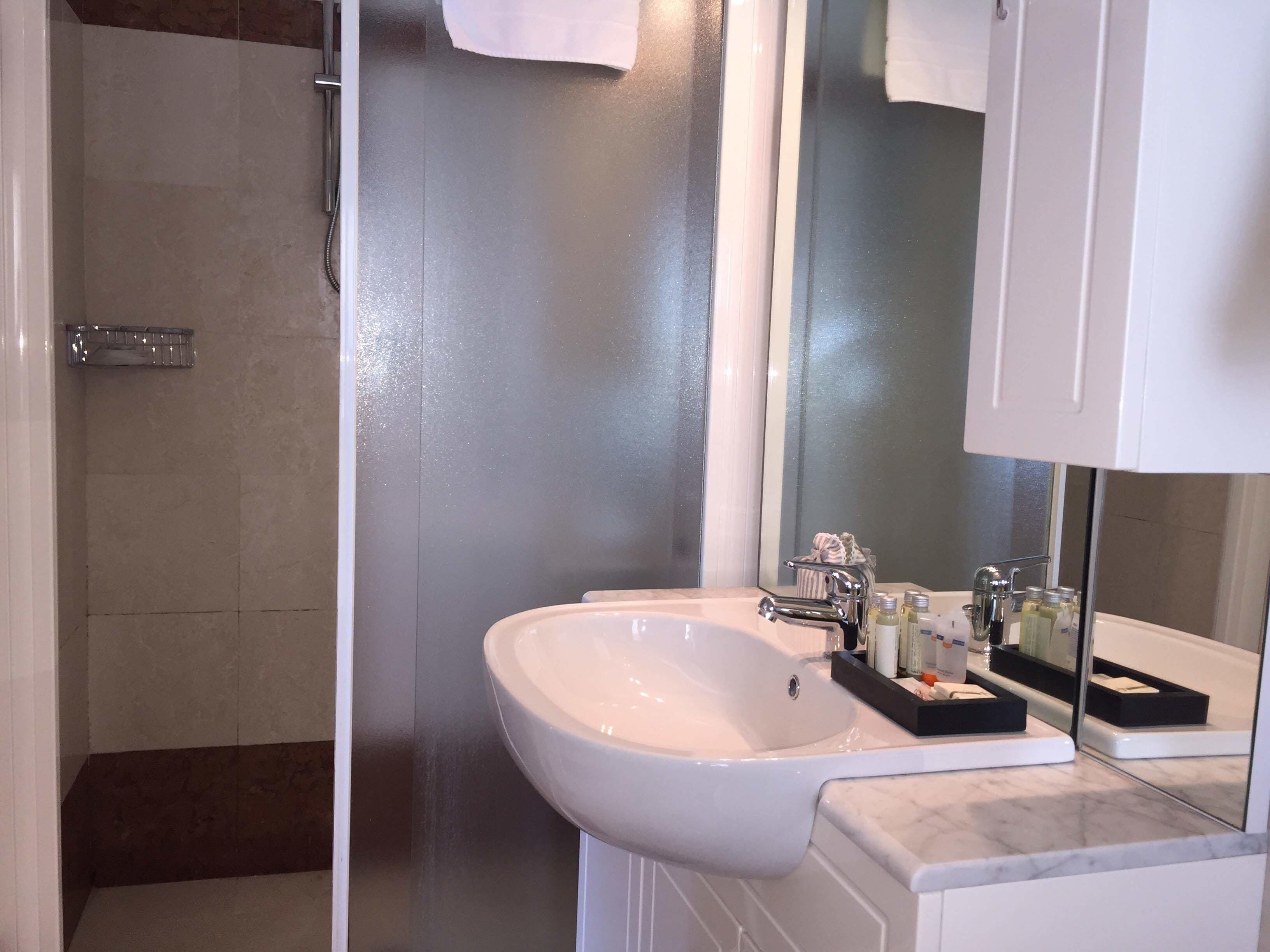 Een badkamer met een wit wastafel, een spiegel en een douche.