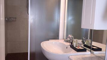 Een badkamer met een wit wastafel, een spiegel en een douche.