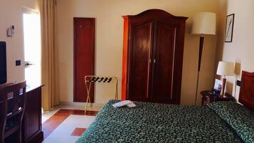 Una habitación de hotel con cama, armario, escritorio y lámpara.