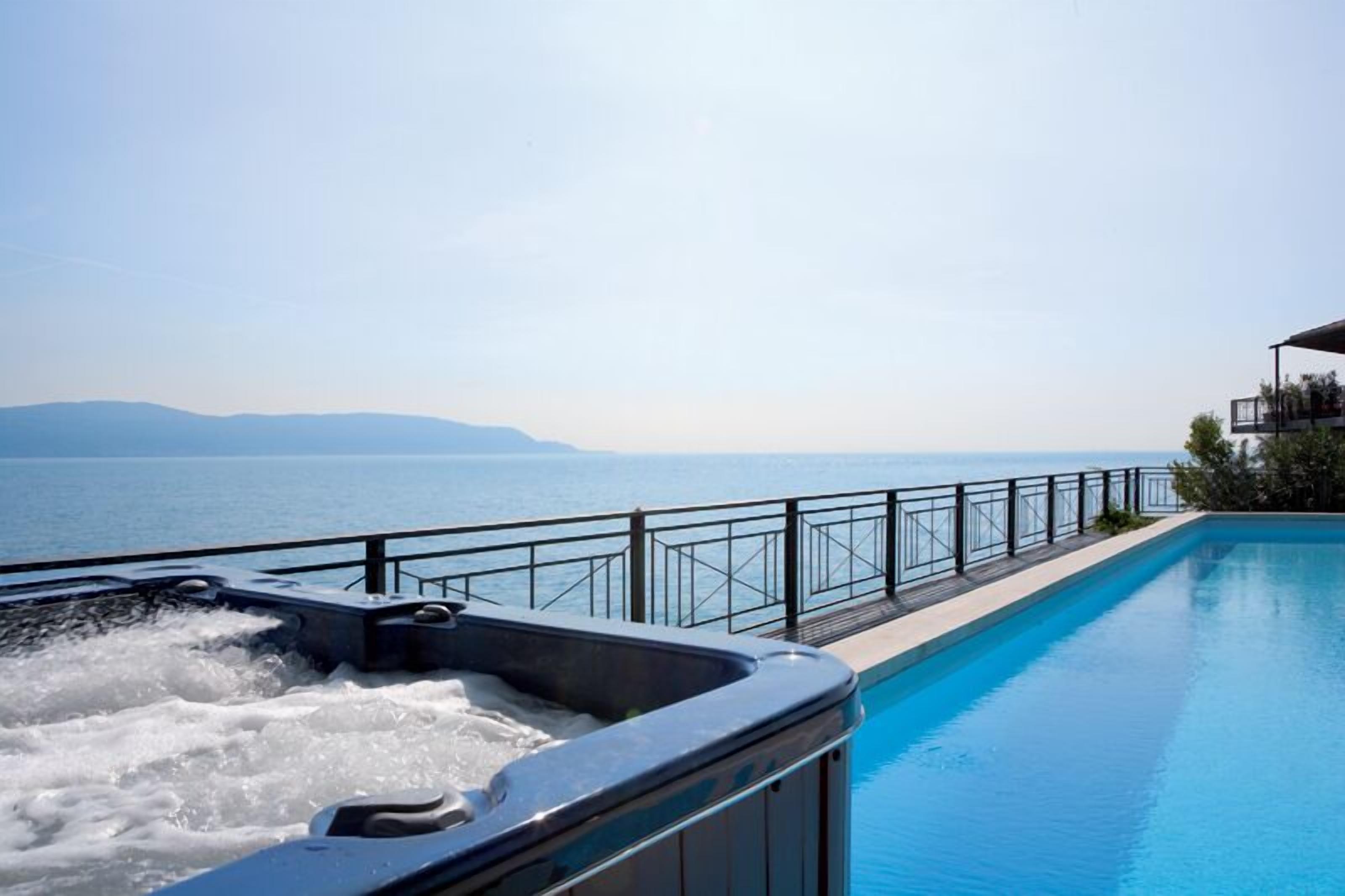 A swimming pool with a hot tub and a view of the sea.