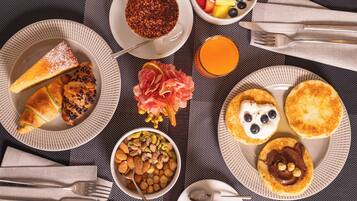 A breakfast table with various food items, including toast, pastries, fruit, and a bowl of nuts.