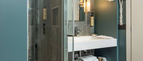 A modern bathroom with a glass shower enclosure, a white sink, and a mirror.
