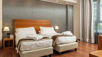 Une chambre d’hôtel avec deux lits, des têtes de lit en bois et une grande fenêtre avec des rideaux.