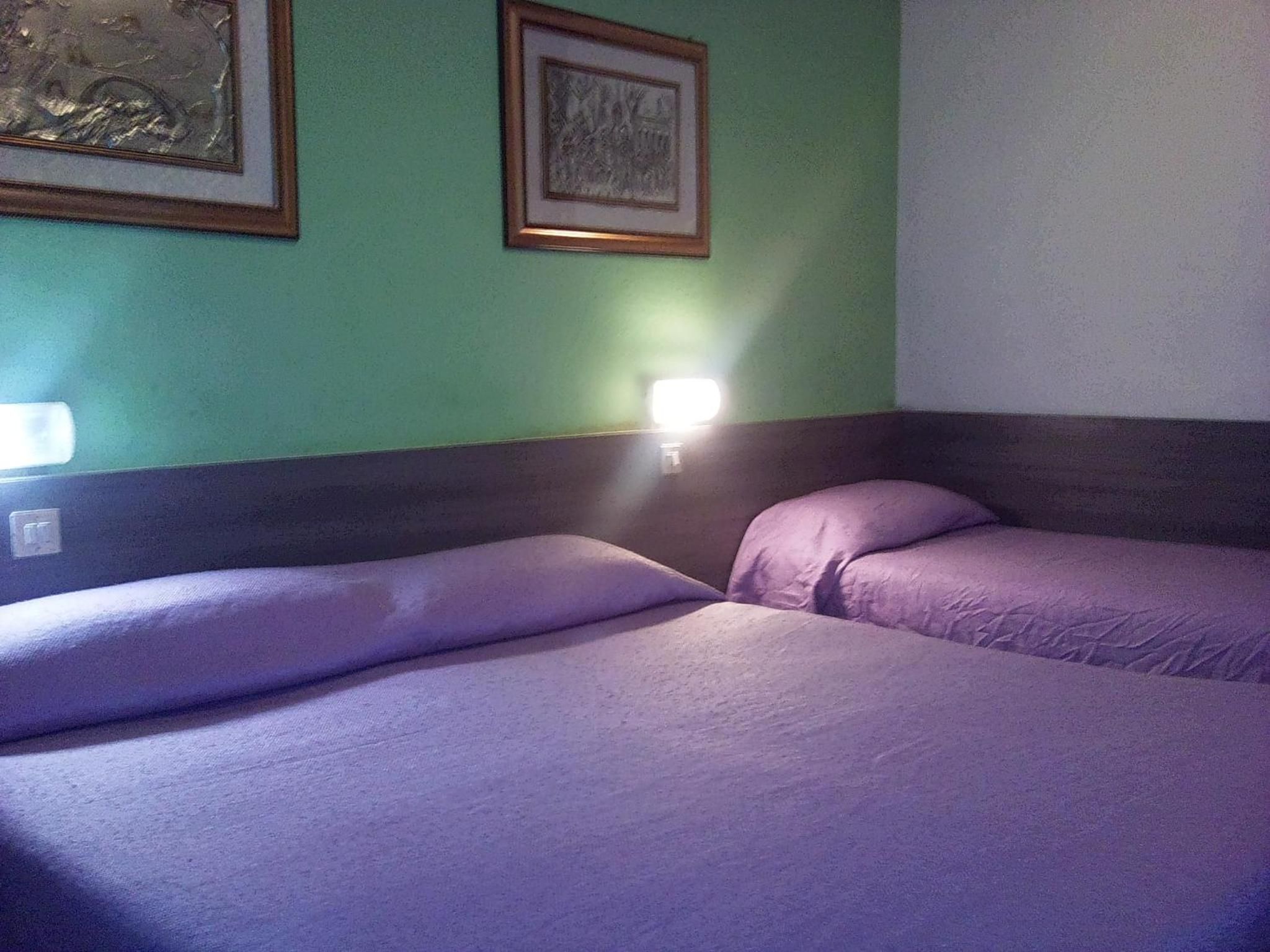 Una stanza con due letti, un comodino e una lampada a muro.
