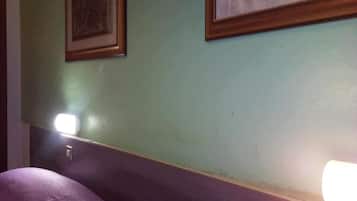 Una stanza con un letto, un comodino e una lampada a muro.