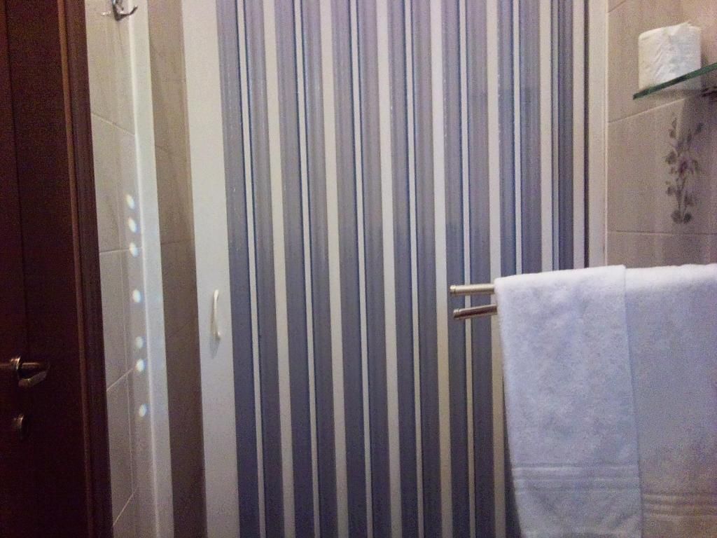 Ein Badezimmer mit gestreiftem Duschvorhang, einem Handtuchhalter und einem Toilettenpapierrollenhalter an der Wand.