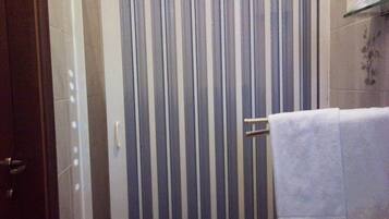 Ein Badezimmer mit gestreiftem Duschvorhang, einem Handtuchhalter und einem Toilettenpapierrollenhalter an der Wand.