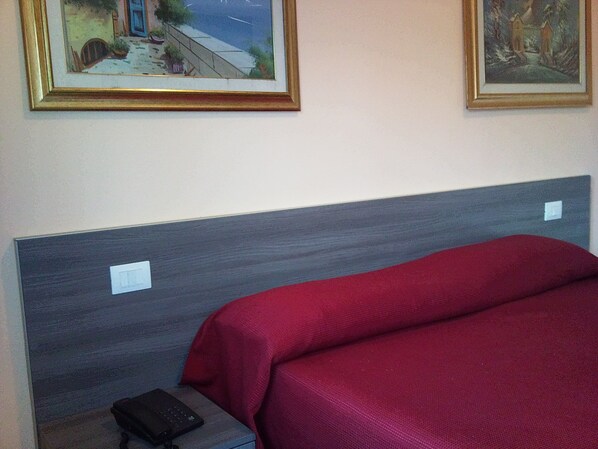 A hotel room with a bed, a nightstand, and two framed pictures on the wall. - Hotel Bristol (Sesto San Giovanni)