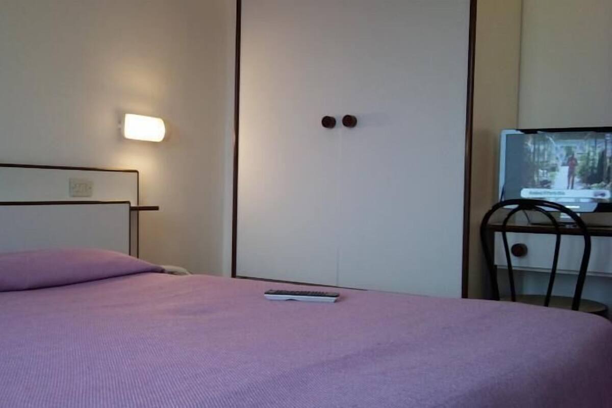 A bedroom with a bed, a nightstand, a TV, and a wardrobe.