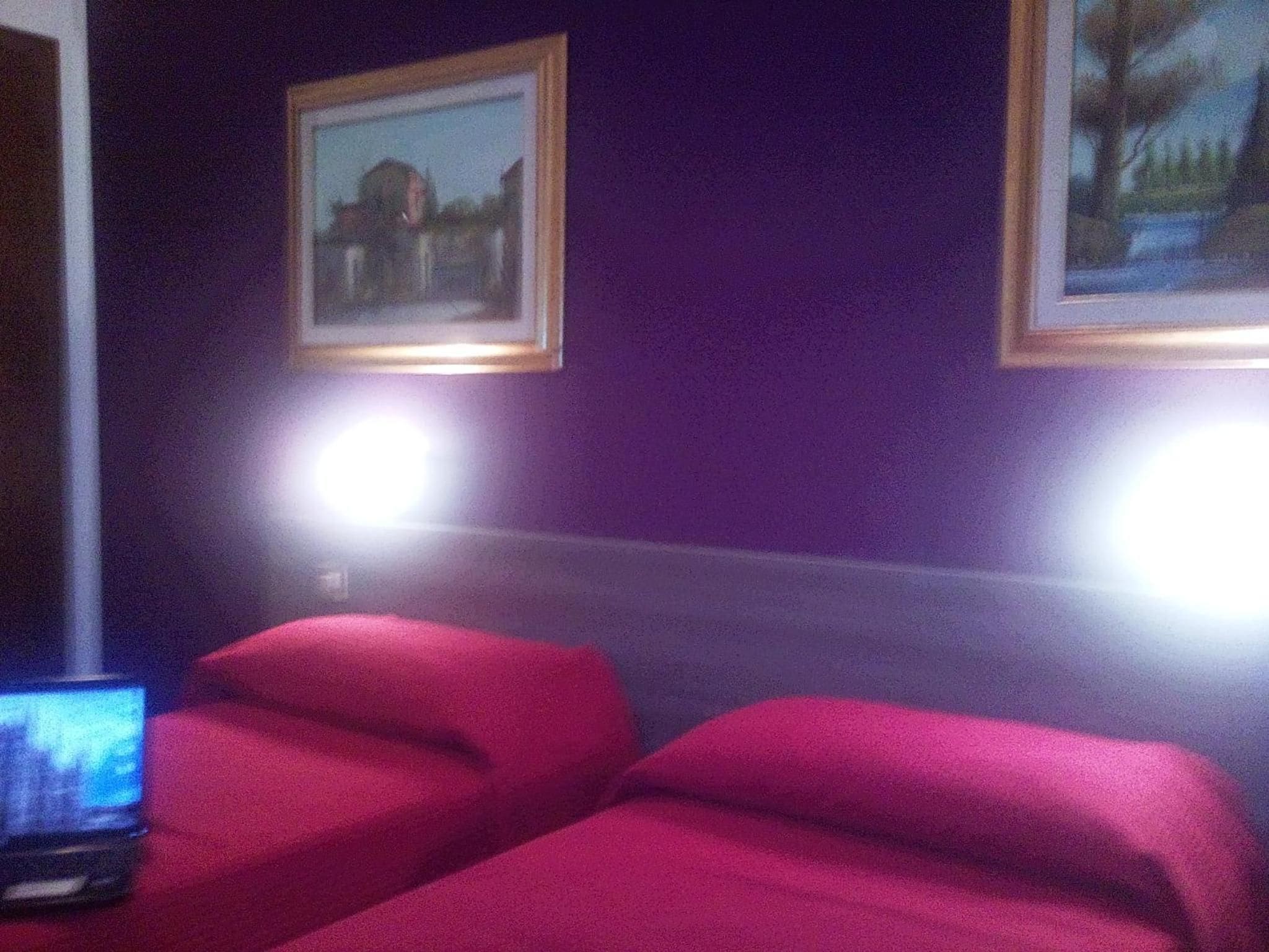 Una habitación con dos camas, un escritorio con una computadora portátil y dos cuadros en la pared.