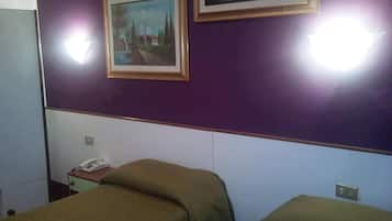 Ein Hotelzimmer mit zwei Betten, einem Nachttisch mit Telefon und zwei gerahmten Bildern an der Wand.