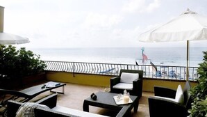 A balcony with outdoor furniture, a white umbrella, and a view of the sea. - Hotel Albatros Varigotti (Finale Ligure)