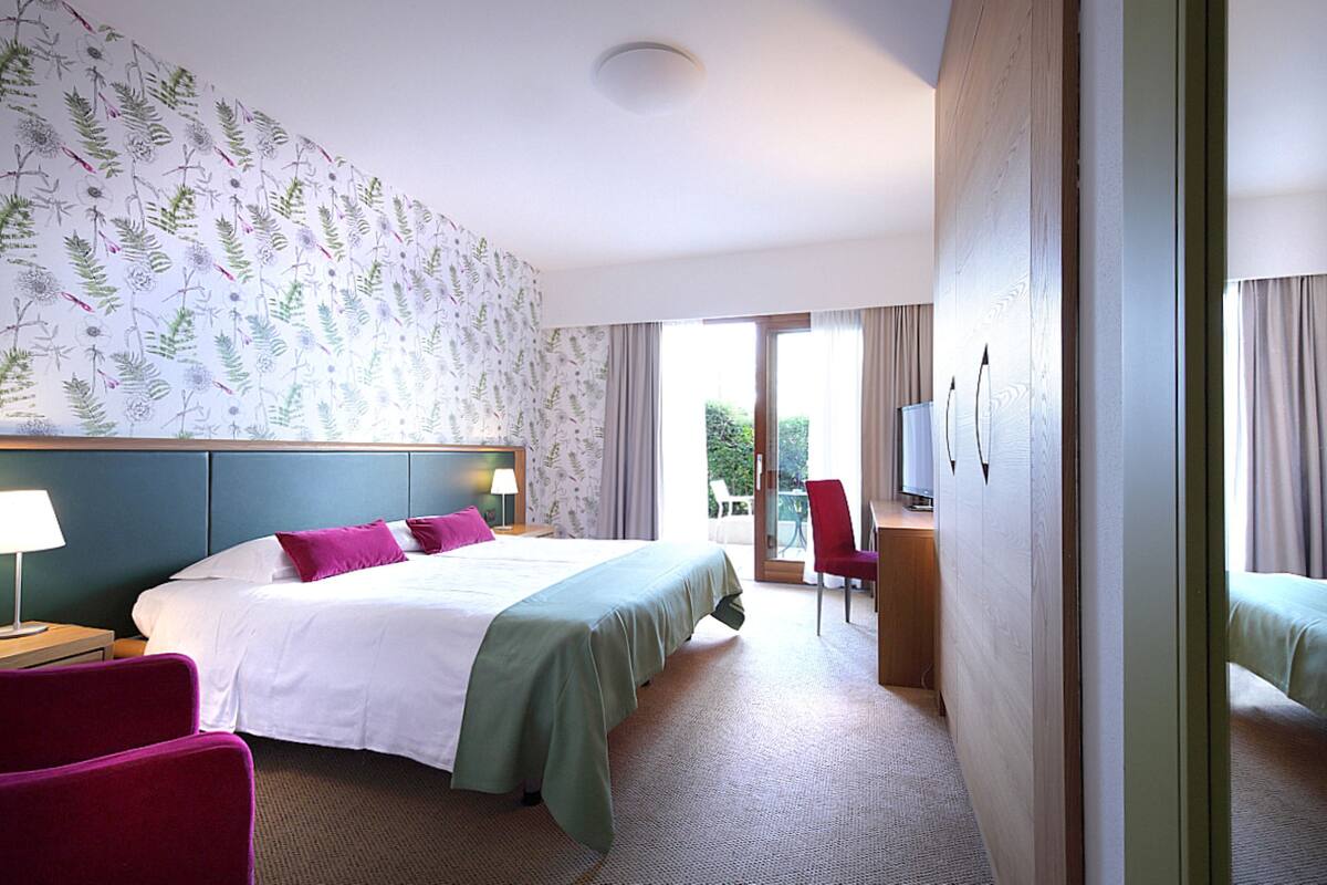 A hotel room with a bed, a desk, a chair, and a television.