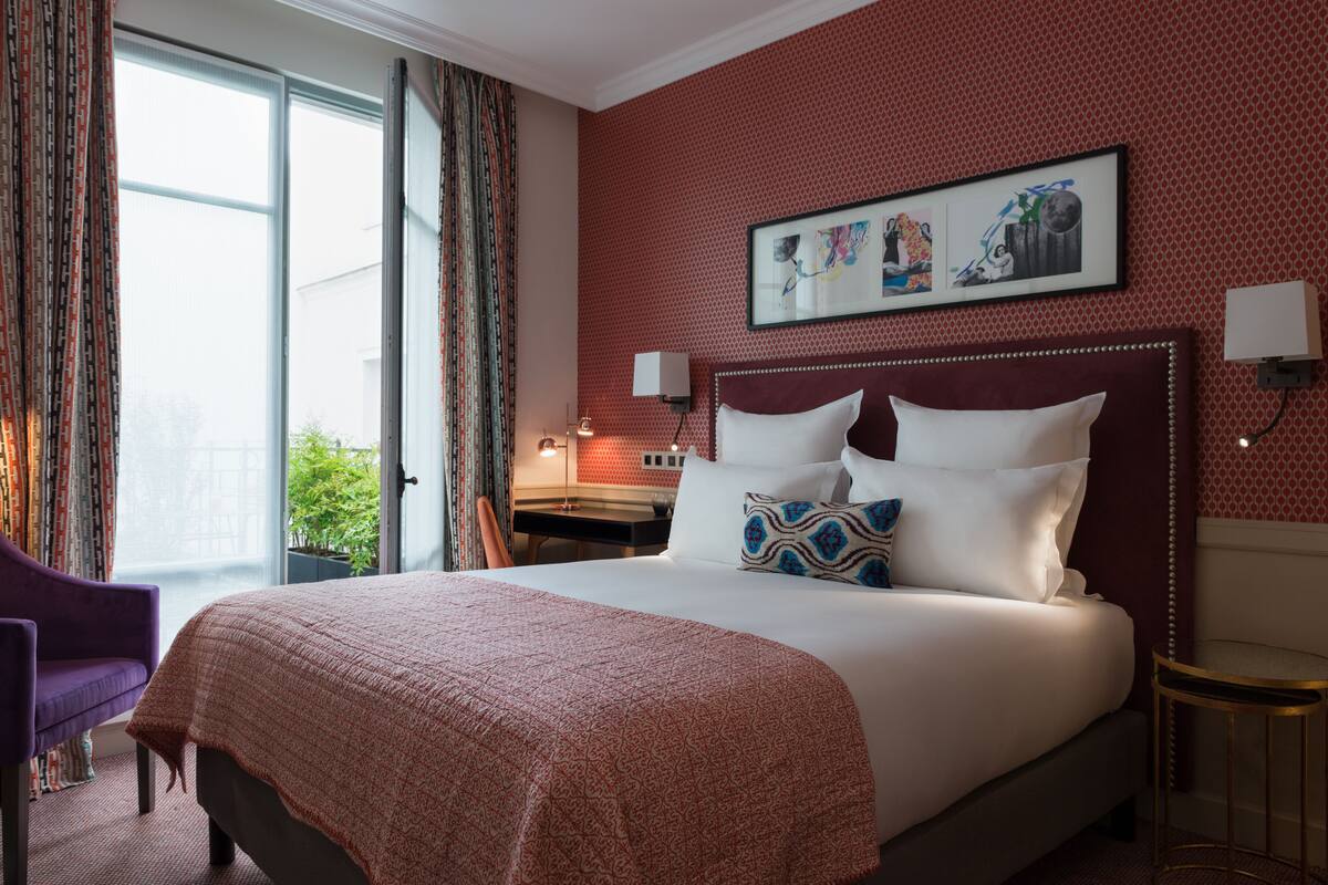 A hotel room with a large bed, a desk, and a chair.