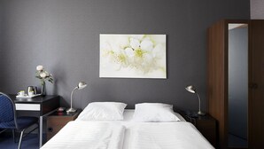 A hotel room with a bed, two bedside tables, a desk with a chair, a wall-mounted painting, and a wardrobe. - Hotel d'Amsterdam (Amsterdam)