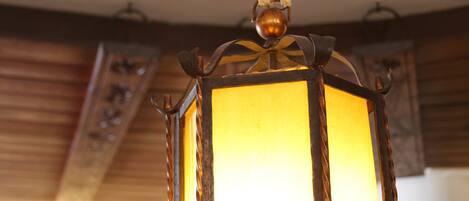 A brass trumpet-shaped light fixture with a lantern hanging below it.