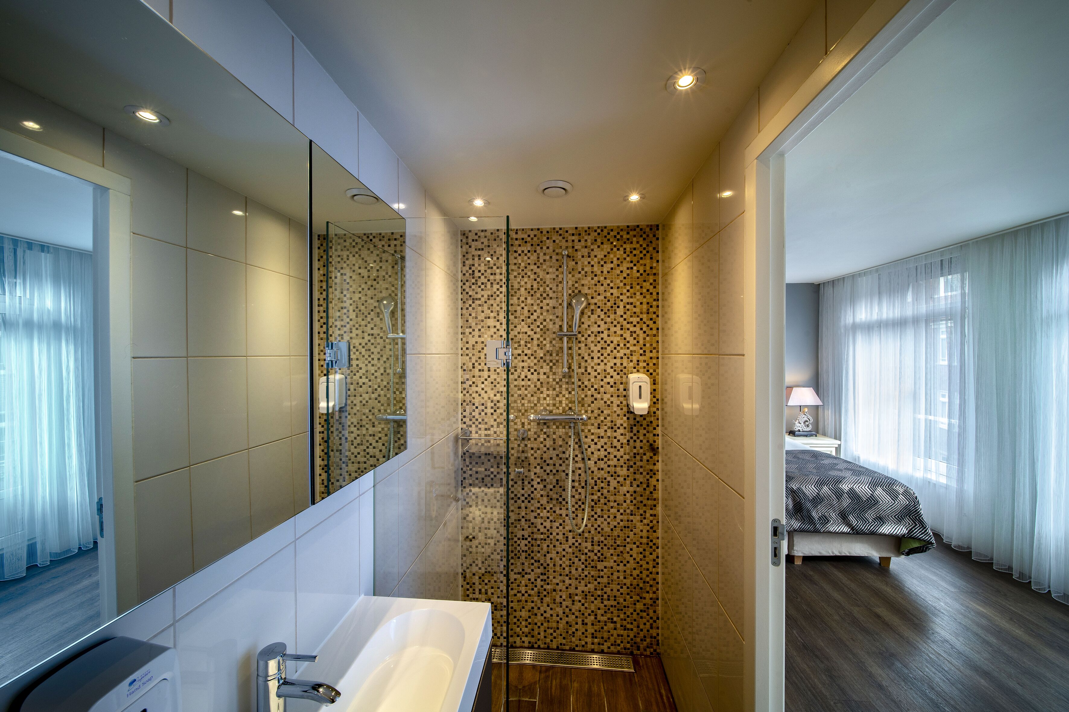 A modern bathroom with a glass-enclosed shower, a large mirror, and a separate toilet area.