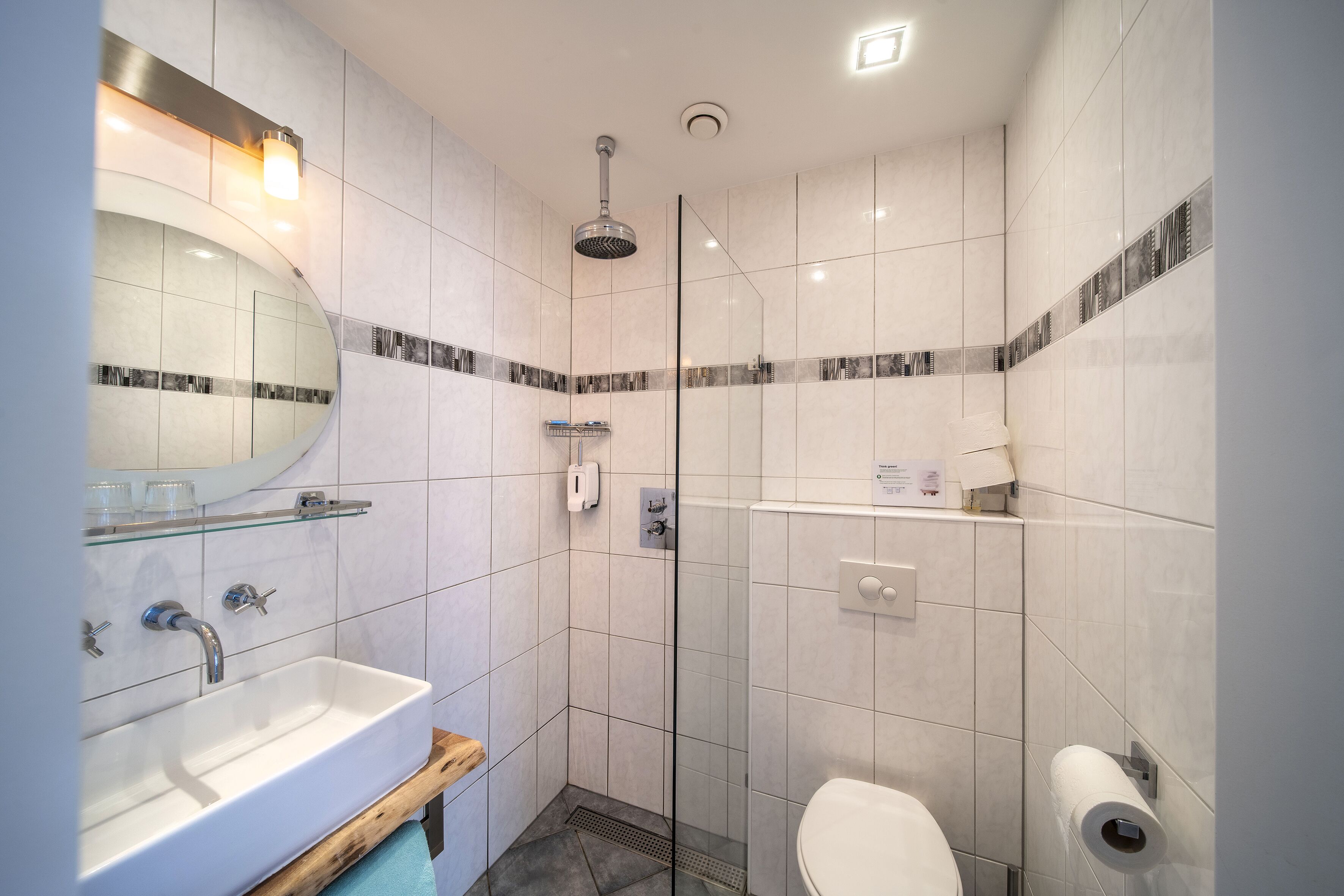 Une salle de bain moderne avec une douche à parois de verre, un lavabo blanc et des toilettes.