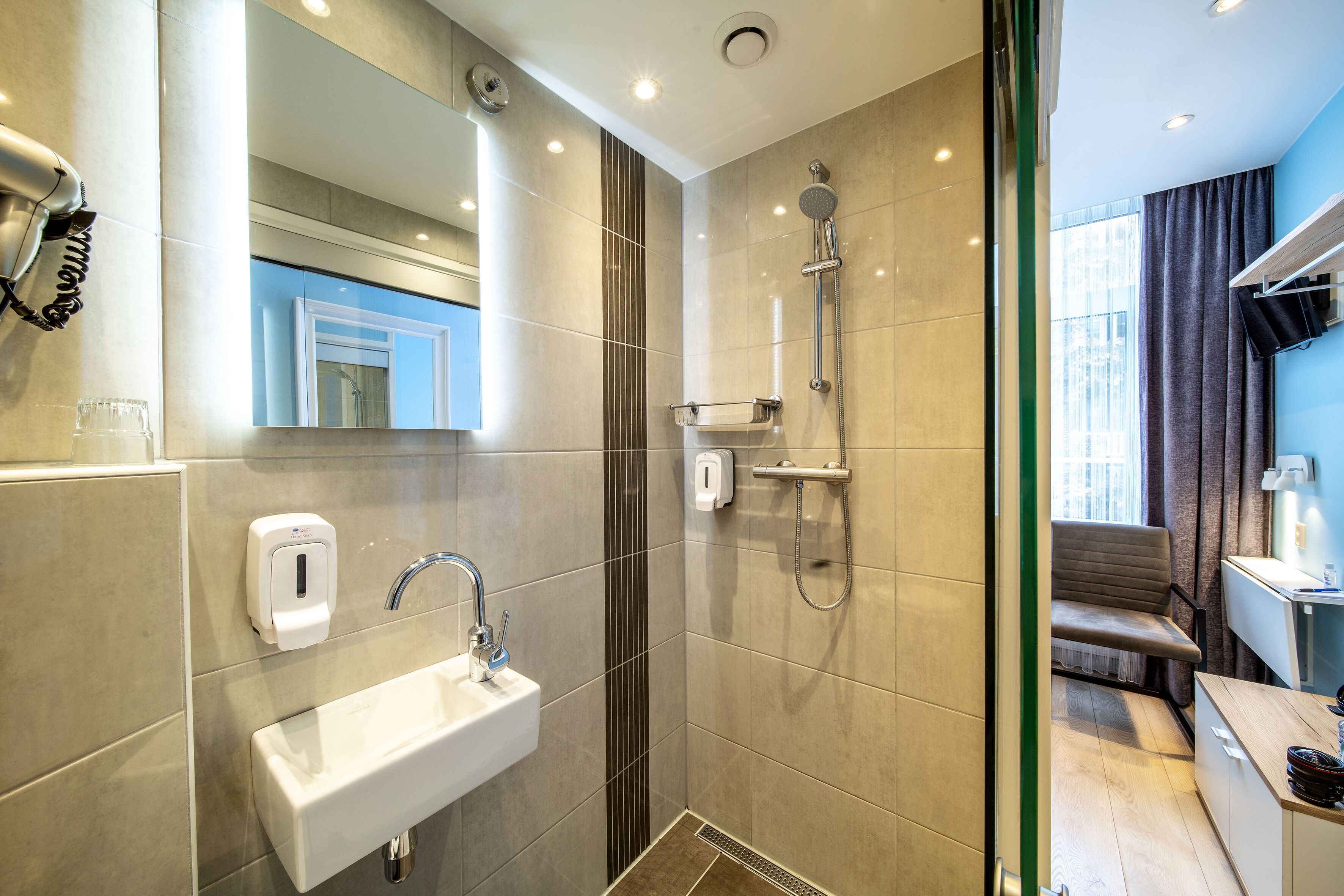 A modern bathroom with a sink, mirror, and shower.